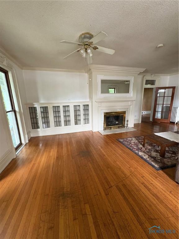 336 Holgate Ave, Defiance, OH 43512 - unfurnished living room with a ceiling fan, wood-type flooring, a textured ceiling, a glass covered fireplace, and crown molding