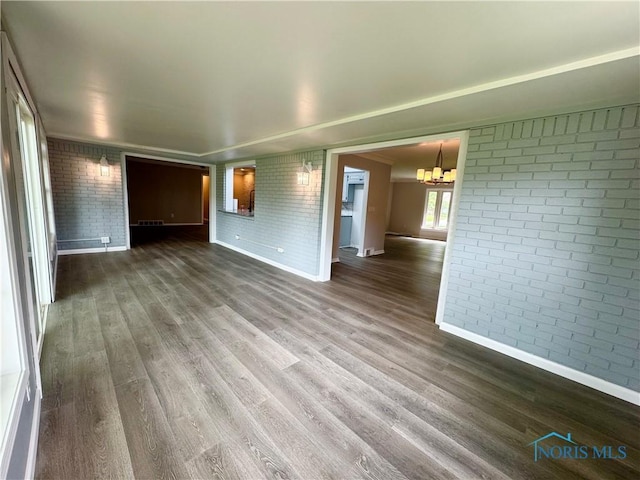 2102 Glen Arbor Dr, Toledo, OH 43614 - unfurnished room featuring brick wall, a chandelier, baseboards, and wood finished floors