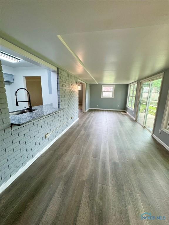 2102 Glen Arbor Dr, Toledo, OH 43614 - unfurnished living room featuring a sink, wood finished floors, baseboards, and brick wall