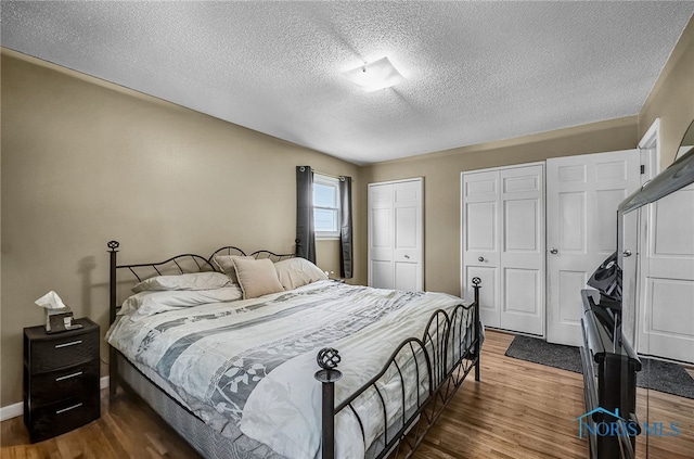 864 Maple Ln, Waterville, OH 43566 - bedroom with two closets, a textured ceiling, and wood finished floors