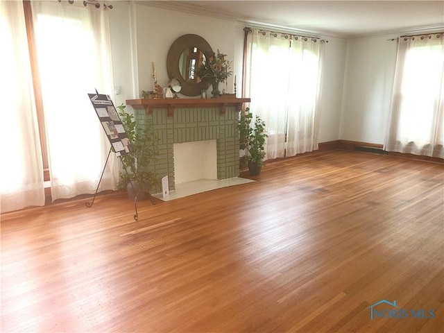 117 3rd St, Findlay, OH 45840 - unfurnished living room featuring crown molding, wood finished floors, plenty of natural light, and a fireplace