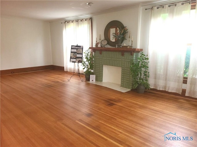 117 3rd St, Findlay, OH 45840 - unfurnished living room with healthy amount of natural light, ornamental molding, wood finished floors, a brick fireplace, and baseboards