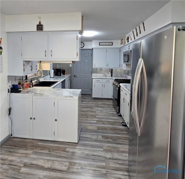 1154 Lagrange St, Napoleon, OH 43545 - kitchen featuring appliances with stainless steel finishes, a peninsula, wood finished floors, light countertops, and white cabinetry
