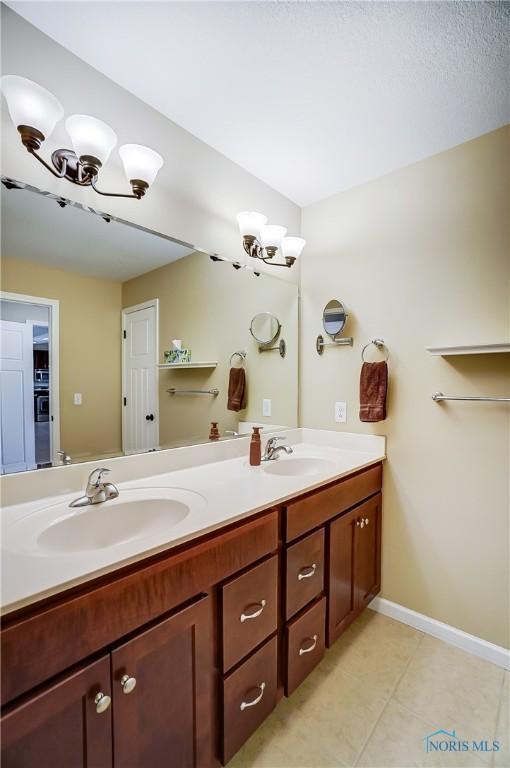 8971 N Park Lake Cir, Sylvania, OH 43560 - full bathroom featuring a chandelier, double vanity, and tile patterned flooring