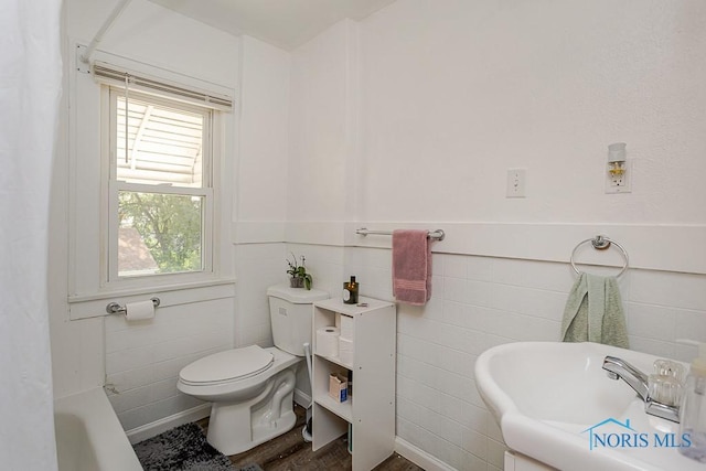 4405 Vermaas Ave, Toledo, OH 43612 - bathroom with a bath, a wainscoted wall, tile walls, and wood finished floors