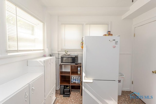 4405 Vermaas Ave, Toledo, OH 43612 - kitchen featuring freestanding refrigerator, stainless steel microwave, light countertops, and white cabinetry