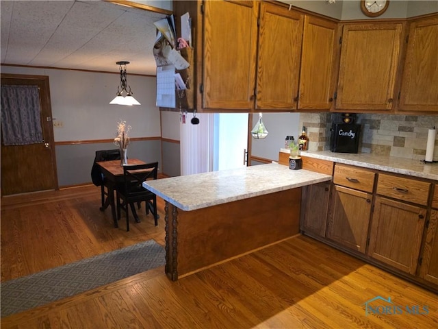 1649 N Perry St, Ottawa, OH 45875 - kitchen with brown cabinets, light countertops, light wood-style floors, a peninsula, and tasteful backsplash
