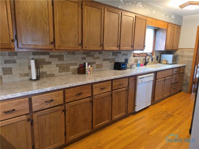 1649 N Perry St, Ottawa, OH 45875 - kitchen with dishwasher, brown cabinets, light wood-style flooring, and backsplash