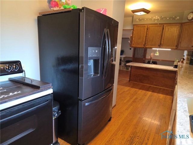 1649 N Perry St, Ottawa, OH 45875 - kitchen with electric stove, stainless steel refrigerator with ice dispenser, brown cabinetry, light wood finished floors, and light countertops