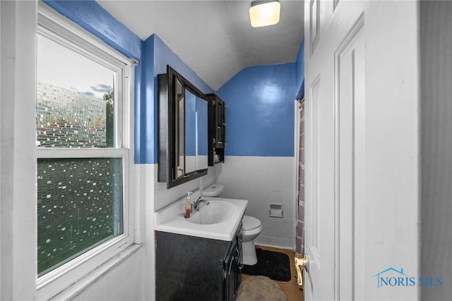 734 Waybridge Rd, Toledo, OH 43612 - bathroom featuring vanity, toilet, lofted ceiling, tile walls, and wainscoting