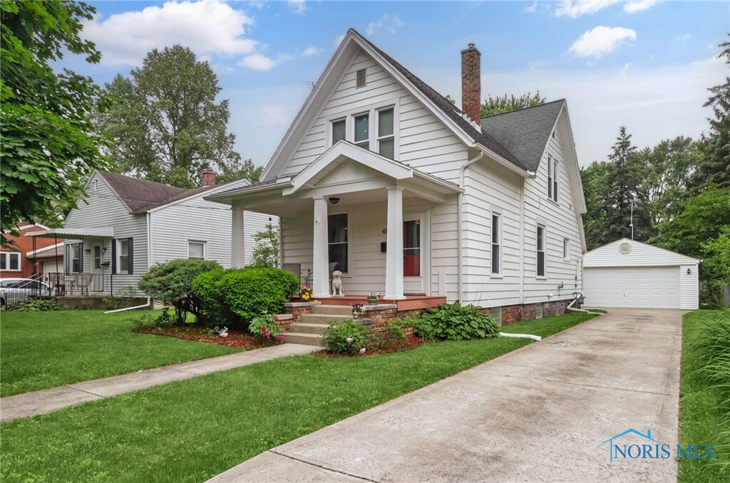 416 Buttonwood Ave, Bowling Green, OH 43402 - bungalow featuring a porch, an outbuilding, a garage, a chimney, and a front lawn