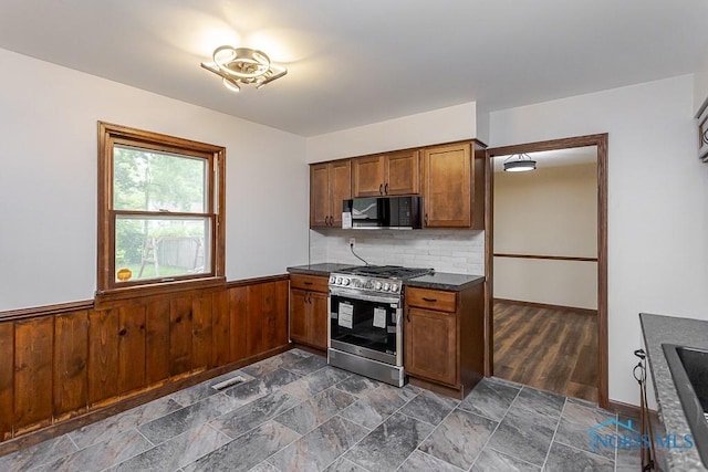 716 Maple St, Perrysburg, OH 43551 - kitchen featuring stainless steel gas stove, black microwave, dark countertops, a wainscoted wall, and tasteful backsplash