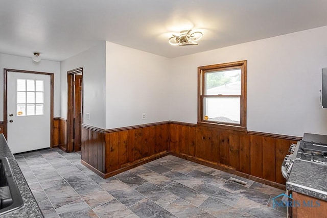 716 Maple St, Perrysburg, OH 43551 - unfurnished dining area with wainscoting, plenty of natural light, wooden walls, and dark stone finish flooring