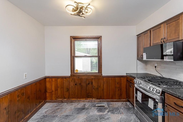 716 Maple St, Perrysburg, OH 43551 - kitchen with stainless steel gas range oven, black microwave, wainscoting, wooden walls, and dark stone finish floors