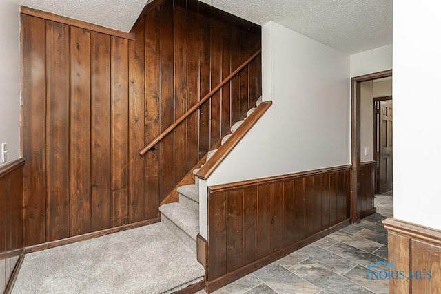716 Maple St, Perrysburg, OH 43551 - stairway with wood walls, a textured ceiling, a wainscoted wall, and stone finish flooring