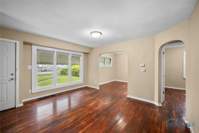 902 Coventry Ave, Toledo, OH 43607 - unfurnished living room with arched walkways, hardwood / wood-style flooring, and baseboards