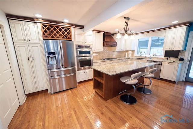 6975 Ramblehurst Rd, Sylvania, OH 43560 - kitchen with stainless steel appliances, premium range hood, tasteful backsplash, light wood finished floors, and recessed lighting