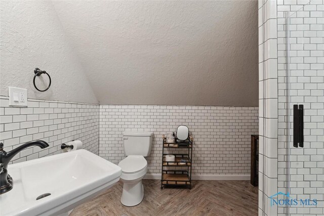 2707 Gunckel Blvd, Toledo, OH 43606 - bathroom with tile walls, vaulted ceiling, a textured wall, a wainscoted wall, and a shower