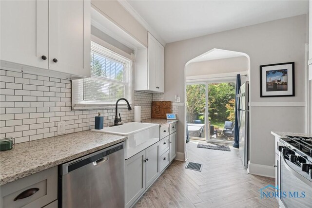 2707 Gunckel Blvd, Toledo, OH 43606 - kitchen with stainless steel appliances, plenty of natural light, decorative backsplash, and white cabinets