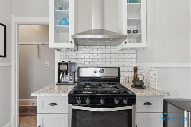 2707 Gunckel Blvd, Toledo, OH 43606 - kitchen featuring stainless steel gas range oven, wall chimney range hood, white cabinetry, light stone counters, and glass insert cabinets