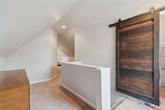 2707 Gunckel Blvd, Toledo, OH 43606 - hallway featuring carpet flooring, an upstairs landing, vaulted ceiling, a barn door, and recessed lighting
