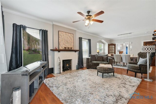 2707 Gunckel Blvd, Toledo, OH 43606 - living room with ornamental molding, ceiling fan, wood finished floors, a wood stove, and arched walkways