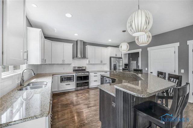 9211 Stable Creek Ct, Sylvania, OH 43560 - kitchen with wall chimney exhaust hood, stainless steel appliances, dark wood finished floors, white cabinetry, and a kitchen breakfast bar