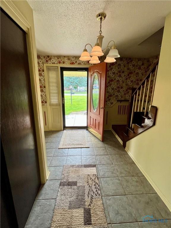 6312 Meadowlark Ln, Payne, OH 45880 - entryway featuring wallpapered walls, a chandelier, wainscoting, and a textured ceiling