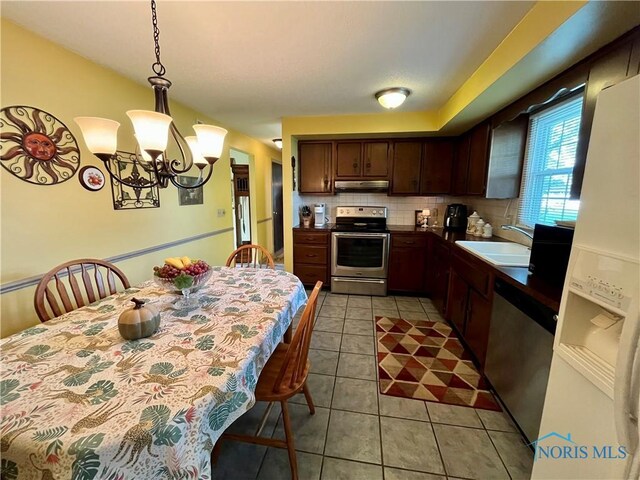 6312 Meadowlark Ln, Payne, OH 45880 - kitchen with stainless steel appliances, under cabinet range hood, a chandelier, light tile patterned flooring, and pendant lighting
