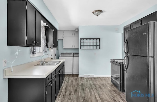 5022 Stengel Ave, Toledo, OH 43614 - kitchen with black appliances, washer and clothes dryer, light wood finished floors, light countertops, and dark cabinetry