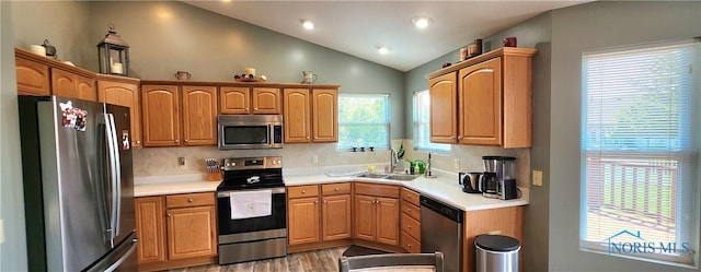 149 Carlee Ln, Findlay, OH 45840 - kitchen featuring appliances with stainless steel finishes, vaulted ceiling, decorative backsplash, light wood-style flooring, and light countertops