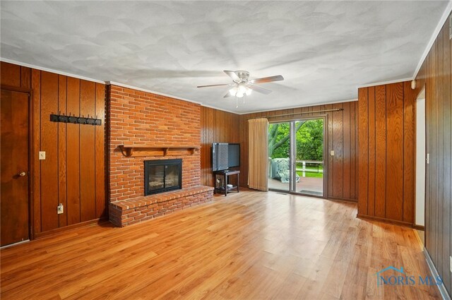 1110 Bourgogne Ave, Bowling Green, OH 43402 - unfurnished living room with a ceiling fan, wooden walls, wood finished floors, a brick fireplace, and ornamental molding