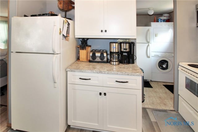 1660 N Compass Ave, Port Clinton, OH 43452 - kitchen with white appliances, stacked washing machine and dryer, white cabinetry, and light stone countertops