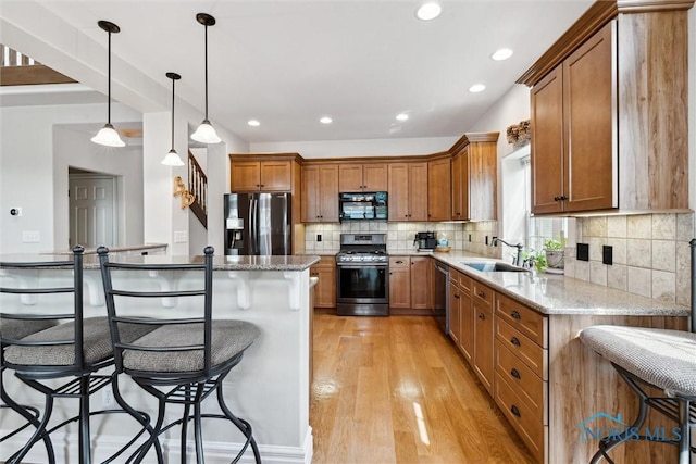 440 W 3rd St, Perrysburg, OH 43551 - kitchen featuring appliances with stainless steel finishes, a kitchen breakfast bar, brown cabinetry, backsplash, and light wood-style flooring