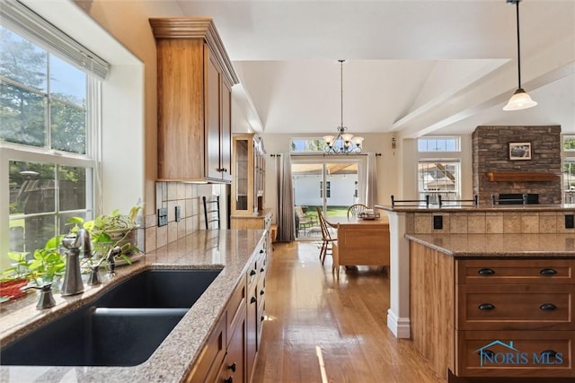 440 W 3rd St, Perrysburg, OH 43551 - kitchen featuring brown cabinetry, light wood finished floors, light stone countertops, a chandelier, and lofted ceiling