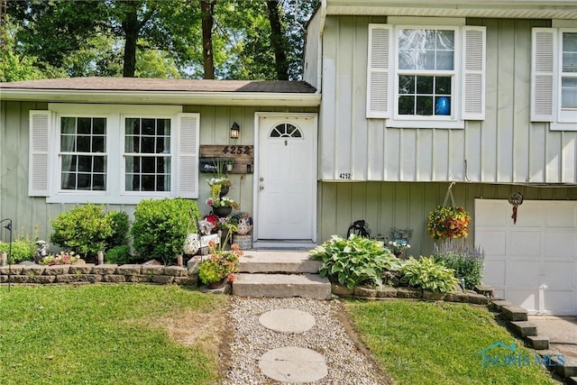 4252 Foxchapel Rd, Toledo, OH 43607 - doorway to property with board and batten siding, an attached garage, and a lawn