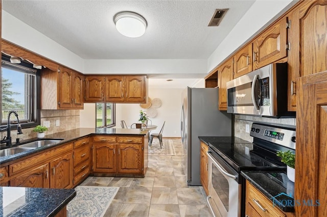 17715 Mitchell Rd, Bowling Green, OH 43402 - kitchen featuring stainless steel appliances, brown cabinets, healthy amount of natural light, tasteful backsplash, and a textured ceiling