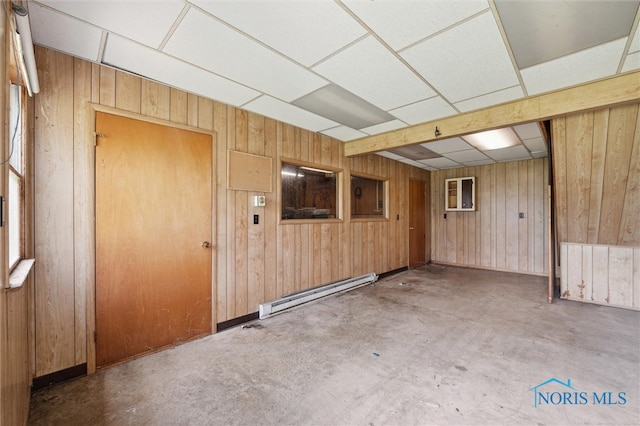 17715 Mitchell Rd, Bowling Green, OH 43402 - spare room with a baseboard heating unit, a paneled ceiling, wood walls, and unfinished concrete flooring