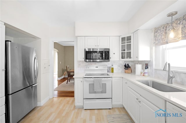 3743 Woodmont Rd, Toledo, OH 43613 - kitchen featuring stainless steel appliances, glass insert cabinets, arched walkways, light wood-style flooring, and white cabinetry