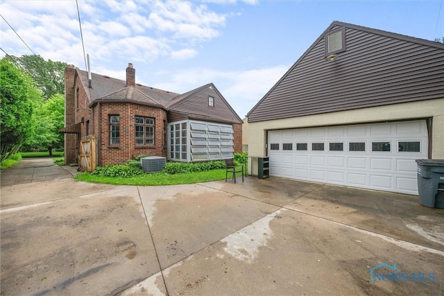 3740 Mapleway Dr, Toledo, OH 43614 - view of home's exterior with brick siding, a chimney, and a garage