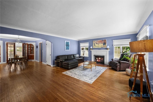 3740 Mapleway Dr, Toledo, OH 43614 - living area featuring arched walkways, a fireplace with flush hearth, wood finished floors, and ornamental molding