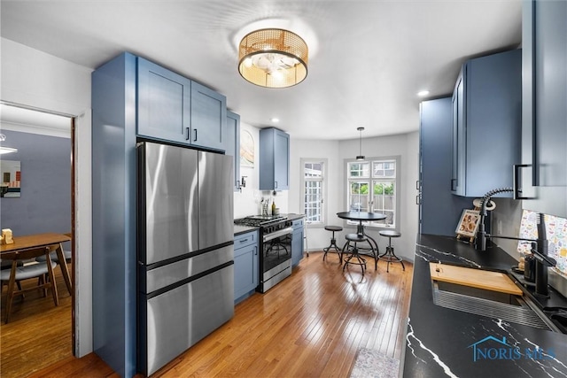 3740 Mapleway Dr, Toledo, OH 43614 - kitchen featuring stainless steel appliances, blue cabinetry, dark countertops, light wood-style floors, and recessed lighting