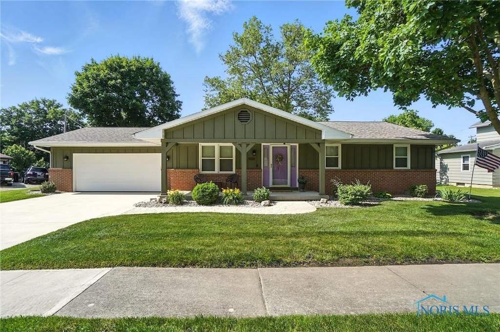 24356 W 3rd St, Grand Rapids, OH 43522 - ranch-style house featuring brick siding, board and batten siding, a front yard, an attached garage, and driveway