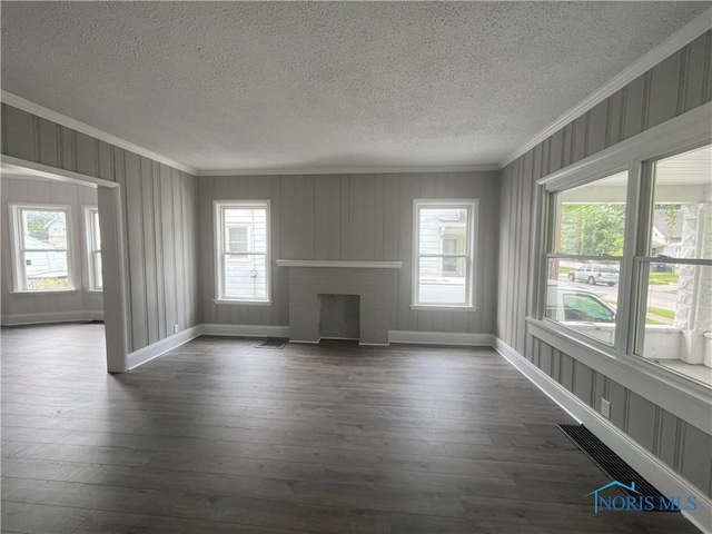 4032 Burnham Ave, Toledo, OH 43612 - unfurnished living room featuring ornamental molding, a textured ceiling, plenty of natural light, a fireplace, and dark wood-type flooring