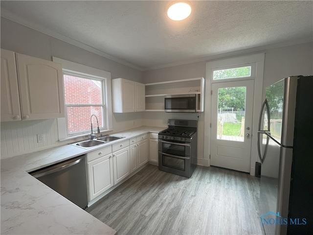 4032 Burnham Ave, Toledo, OH 43612 - kitchen featuring appliances with stainless steel finishes, light wood-style flooring, white cabinets, a textured ceiling, and light stone counters