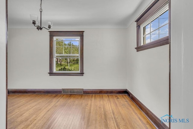 826 4th St, Toledo, OH 43605 - spare room featuring wood finished floors, plenty of natural light, and a chandelier