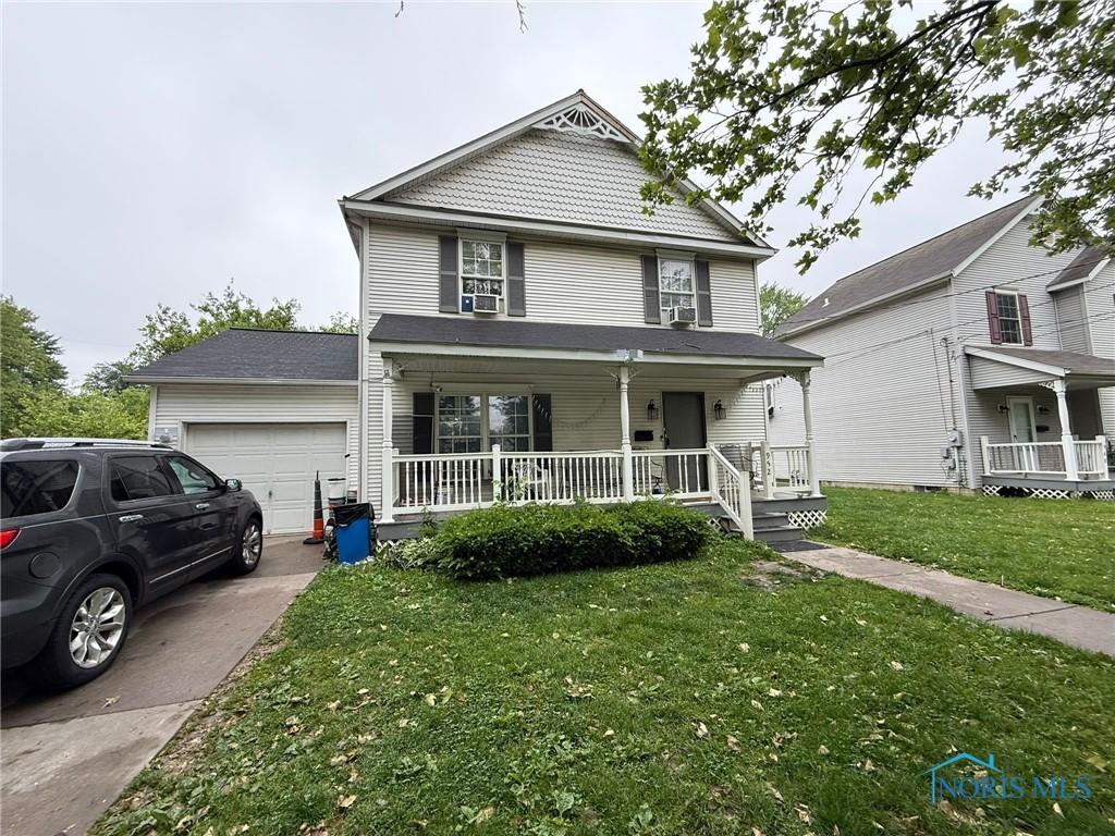 952 Post St, Toledo, OH 43610 - view of front facade featuring a porch, a garage, a front lawn, driveway, and cooling unit