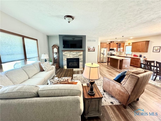 1462 Lee Ann Ave, Defiance, OH 43512 - living room with a textured ceiling, light wood-style flooring, plenty of natural light, and a fireplace