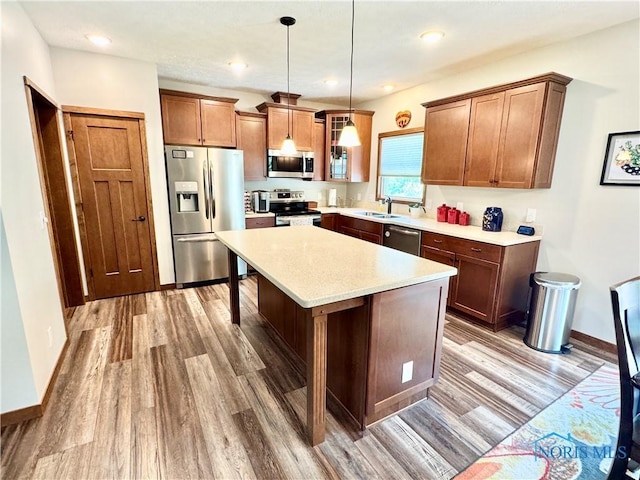 1462 Lee Ann Ave, Defiance, OH 43512 - kitchen featuring appliances with stainless steel finishes, light wood-type flooring, a kitchen island, hanging light fixtures, and light countertops