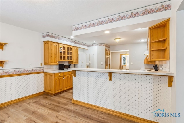 1411 Sawmill Bnd, Findlay, OH 45840 - kitchen with stainless steel microwave, light wood-style floors, a peninsula, open shelves, and a kitchen breakfast bar